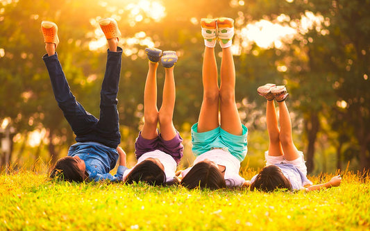 Plusieurs enfants sont allongés sur le dos dans l'herbe, les jambes en l'air.